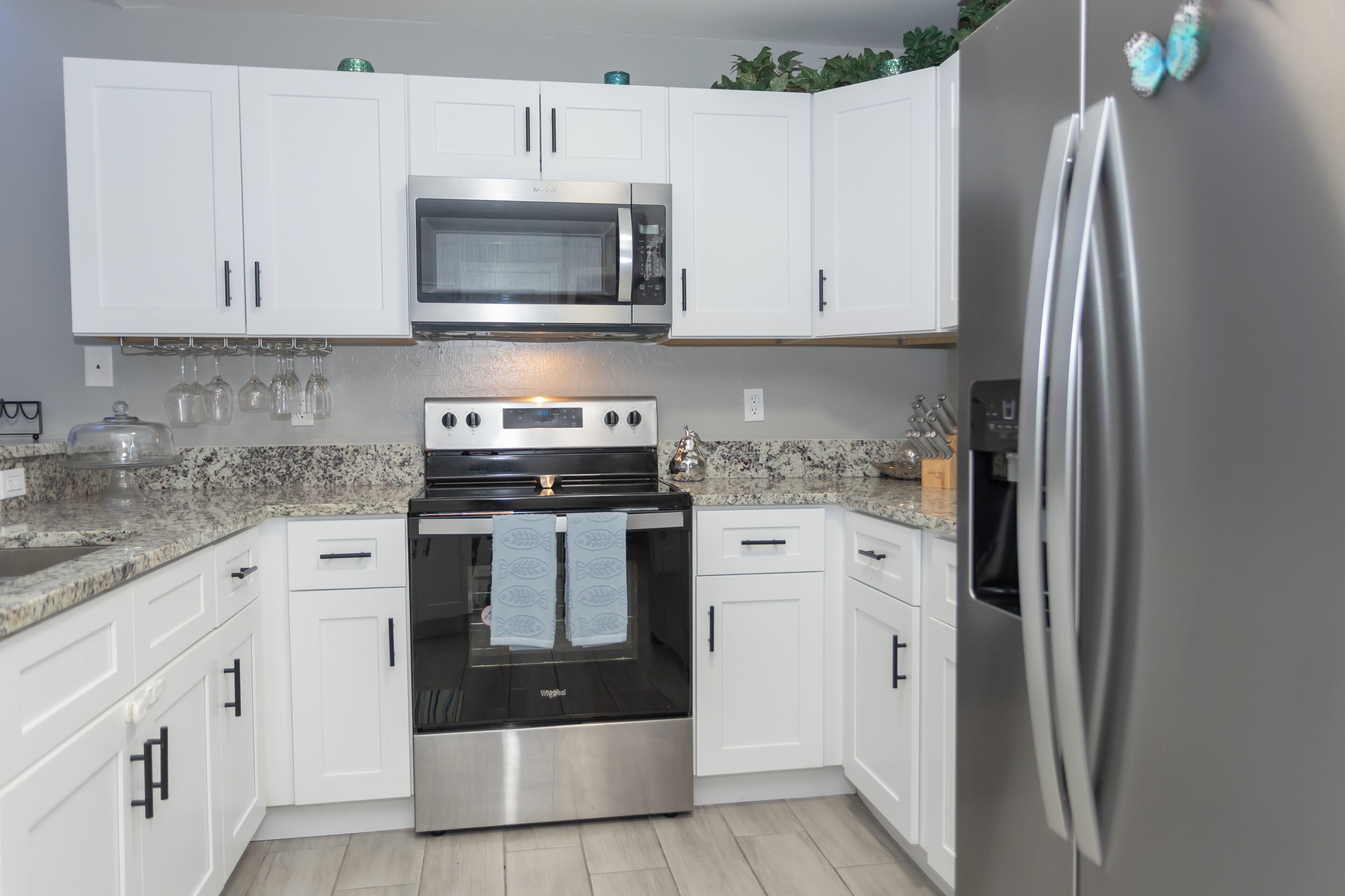 A kitchen with white cabinets, a stainless steel oven, a microwave, and a refrigerator.