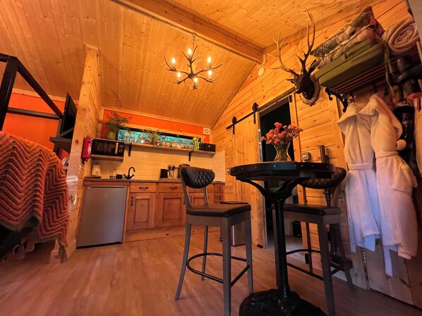 A wooden interior with a chandelier, a kitchen area, and a dining space.