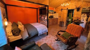 A cozy room with a four-poster bed, a rocking chair, a small kitchen area, and a wooden ceiling. - Cabin, woods, hot tub, stove, coast, porch, remote, private, secure garden. (Grimston)