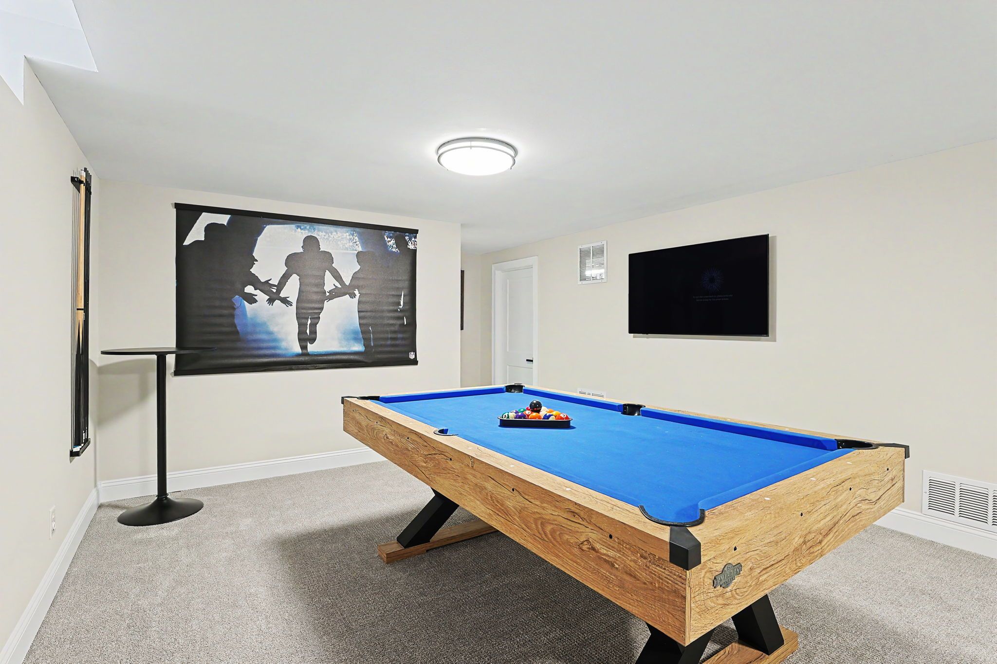 A pool table in a room with a projector screen displaying a silhouette of a person playing pool.