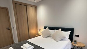 Et moderne soveværelse med seng, sengebord, lampe og dør.