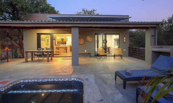Ein modernes Haus mit Terrasse, Pool und Gartenmöbeln.