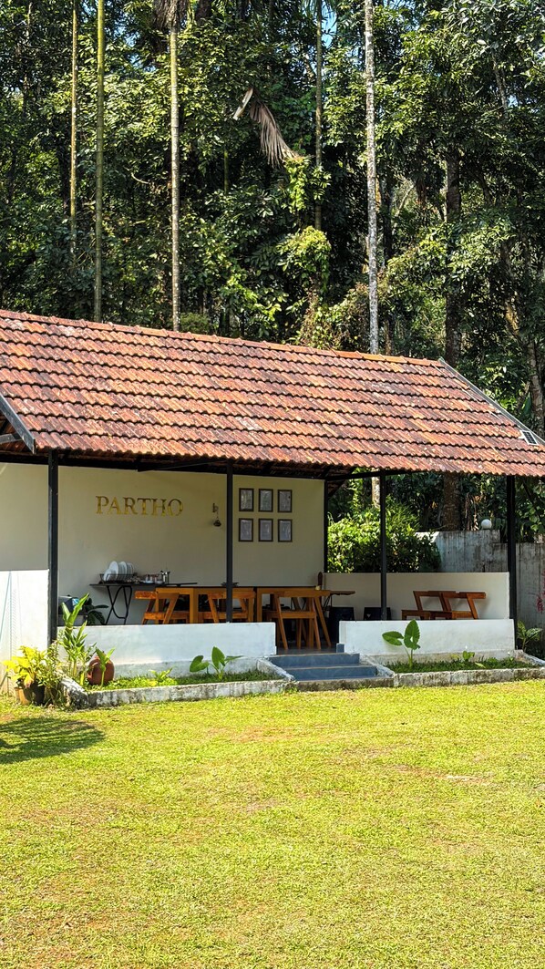 A building with a tiled roof, labeled 'PARTHO,' featuring outdoor seating and a garden area.