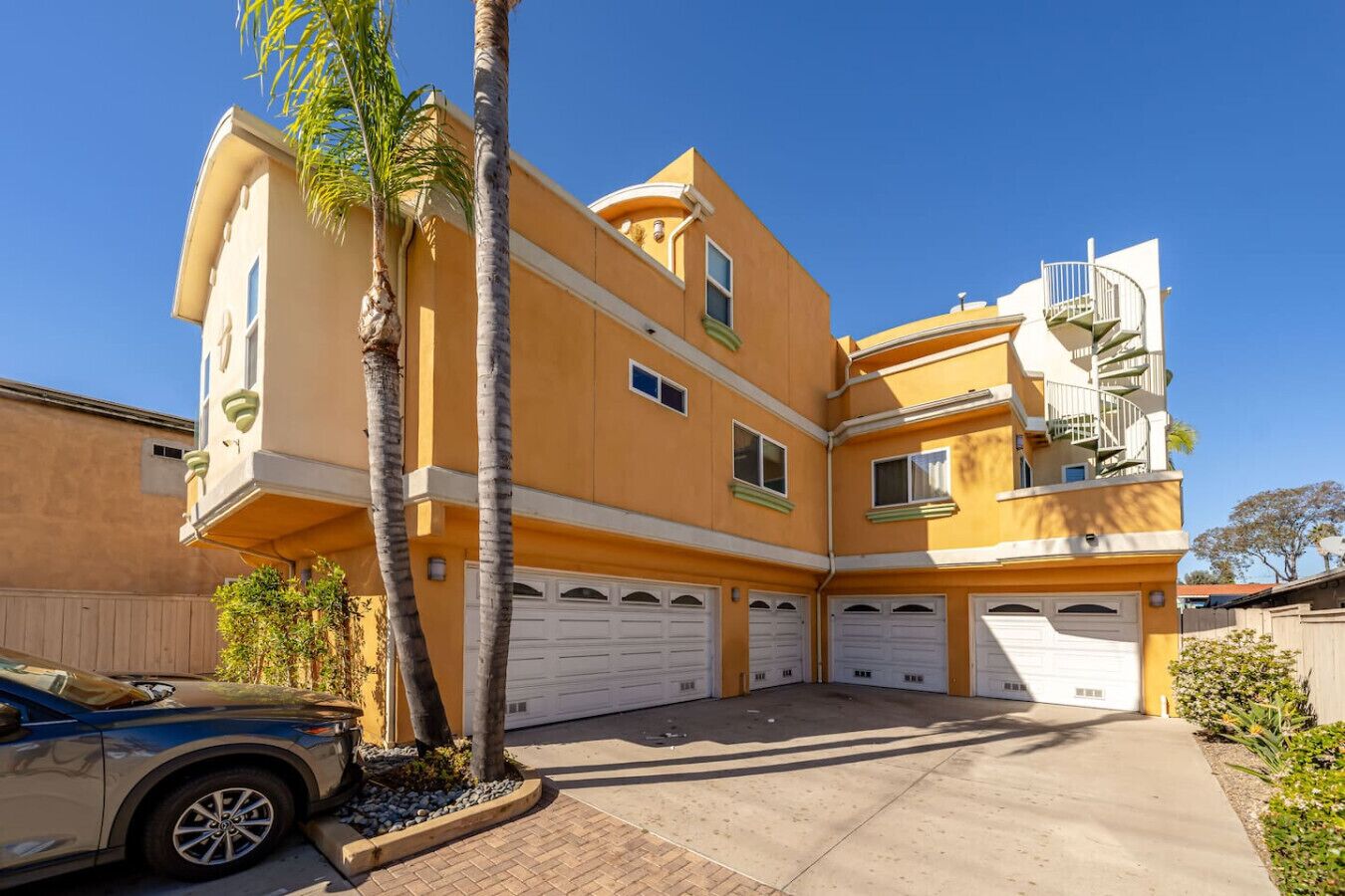A multi-story residential building with a garage, a balcony, and a clear sky.