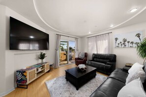 Ein modernes Wohnzimmer mit einem Flachbildfernseher, einem schwarzen Ledersofa, einem Couchtisch und einem farbenfrohen Schrank.