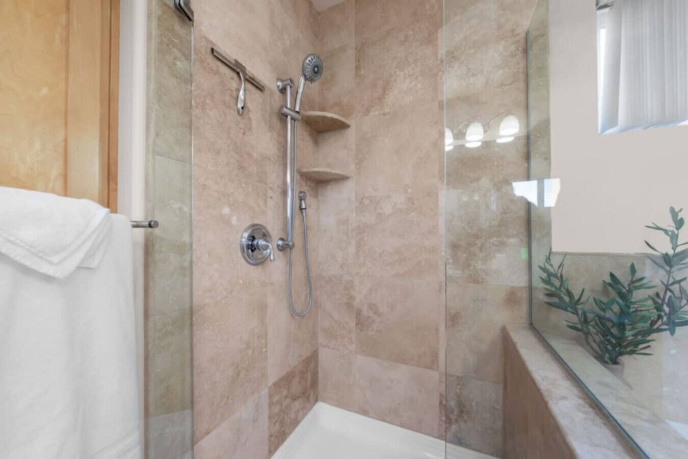 Une salle de bain dotée d’une douche à parois de verre, d’une baignoire blanche et d’une cloison en verre.