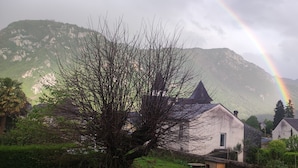 A rural village with traditional houses, a mountain backdrop, and a visible rainbow.
