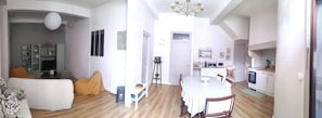 Una sala de estar con un sofá, un televisor y un comedor con una mesa y sillas.