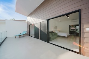 Un interior moderno con un vidrio que da a un dormitorio, un sofá verde y una silla azul.