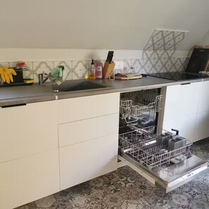 Ett kök med diskmaskin, diskho och en bänkskiva med diverse föremål.