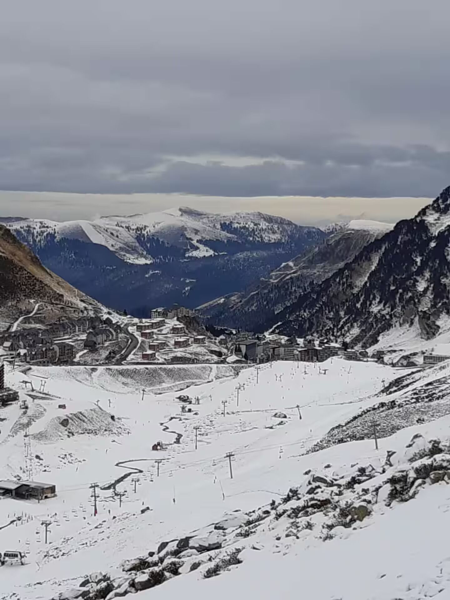 Un paysage montagneux comprenant une station de ski, avec des remontées mécaniques et des bâtiments.