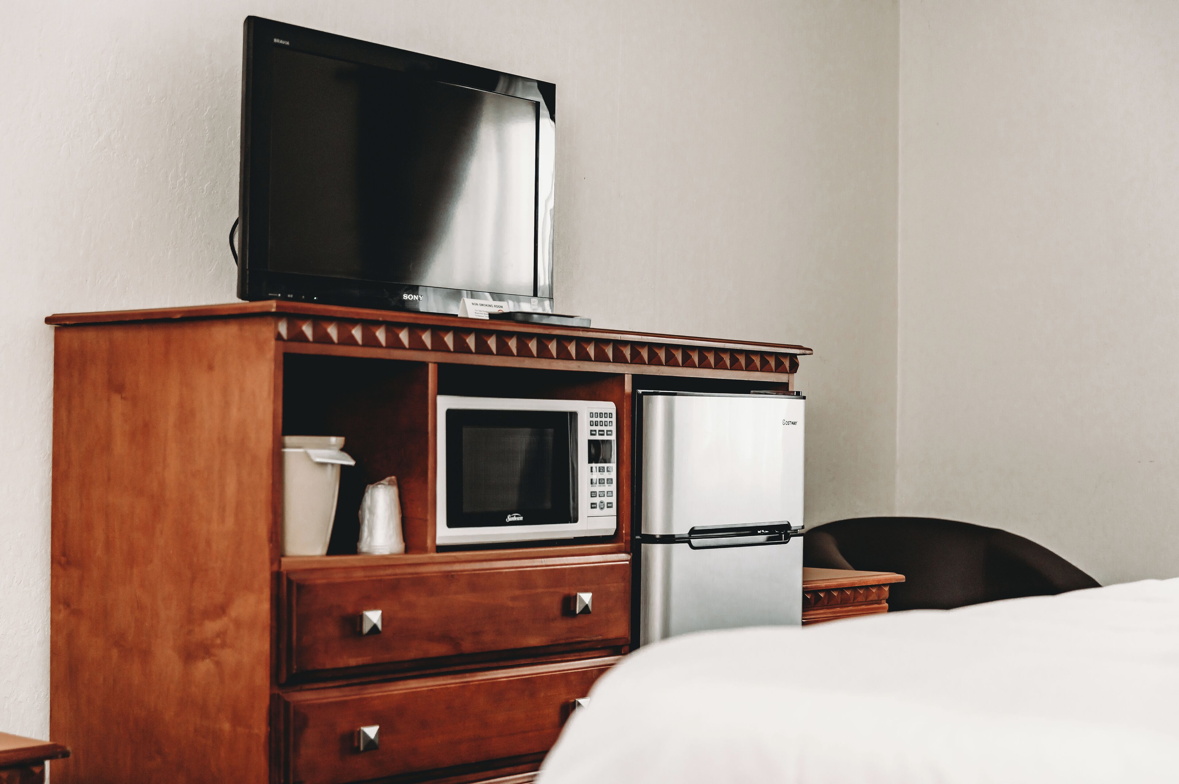 A hotel room with a wooden cabinet containing a television, a microwave, and a refrigerator.