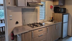 Une cuisine moderne équipée d’une cuisinière à gaz, d’appareils électroménagers en acier inoxydable, de meubles en bois et d’une fenêtre avec des stores.