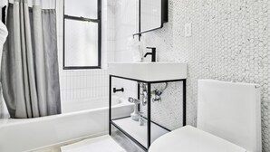 A modern bathroom with a bathtub, a toilet, a sink, and a shower. - 1 Bedroom New Renovated - Wash/Dryer & Kitchenette -E (New York)
