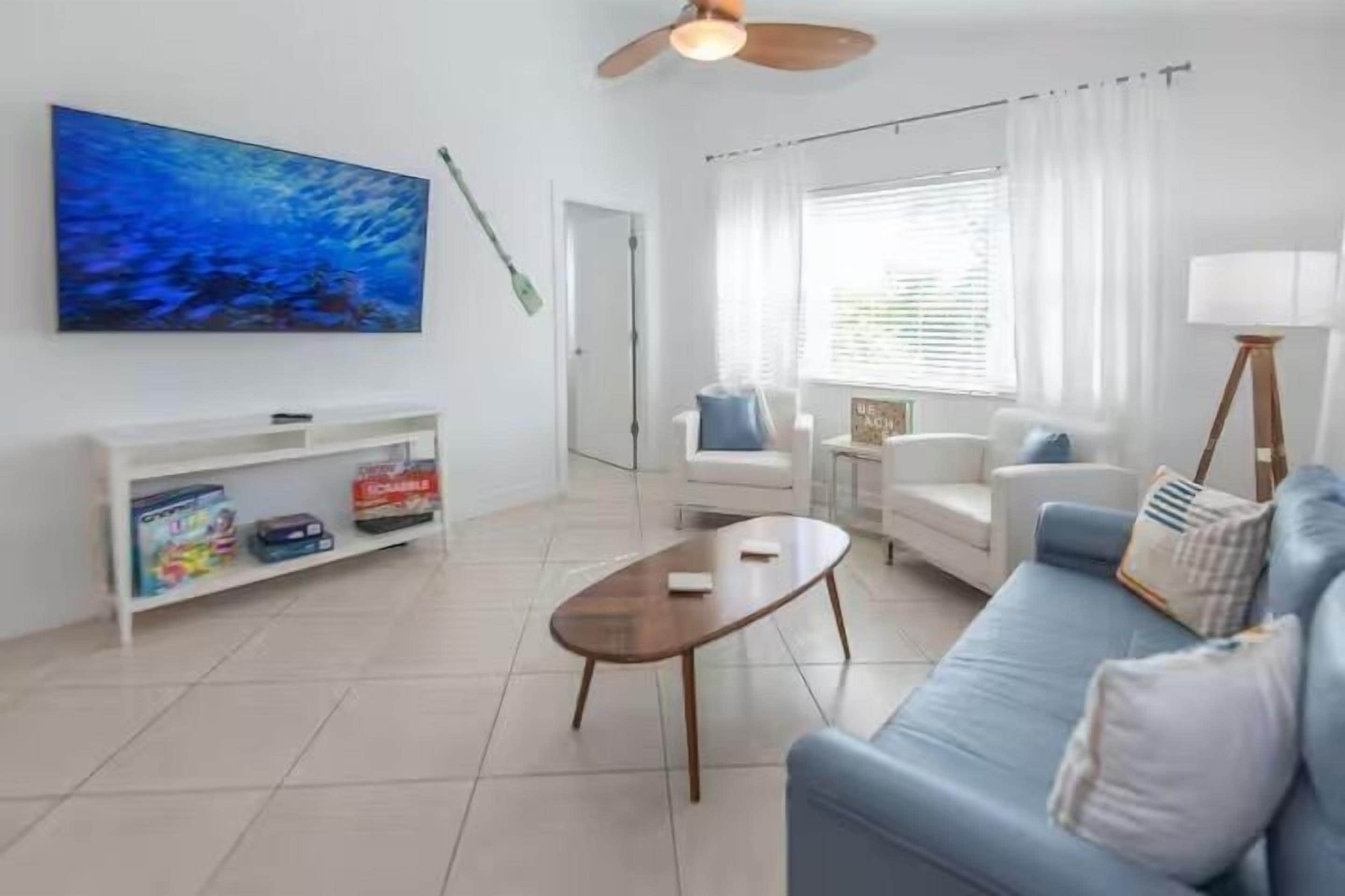 Una sala de estar con sofá, mesa de centro, televisor y estantería.
