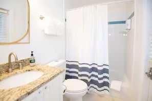 A bathroom with a sink, toilet, and shower curtain. - Sunrise Views & Beach Access | BBQ + Free Parking (Fort Pierce)