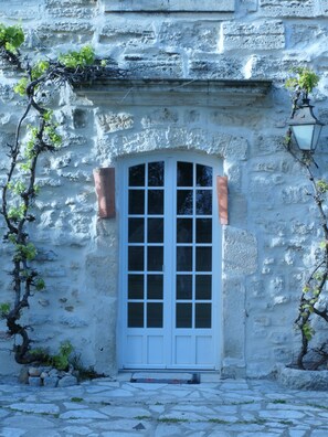Un bâtiment en pierre avec une porte blanche, une petite fenêtre et une lanterne.