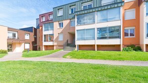 A modern apartment building with multiple floors, large windows, and a central staircase. - Le Soleil Bleu - à 50m de la plage (Courseulles-sur-Mer)