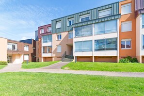 Ein modernes Mehrfamilienhaus mit mehreren Etagen, großen Fenstern und einer zentralen Treppe.