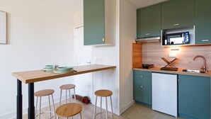 A modern kitchen with a wooden bar, stools, a microwave, and a sink. - Le Soleil Bleu - à 50m de la plage (Courseulles-sur-Mer)
