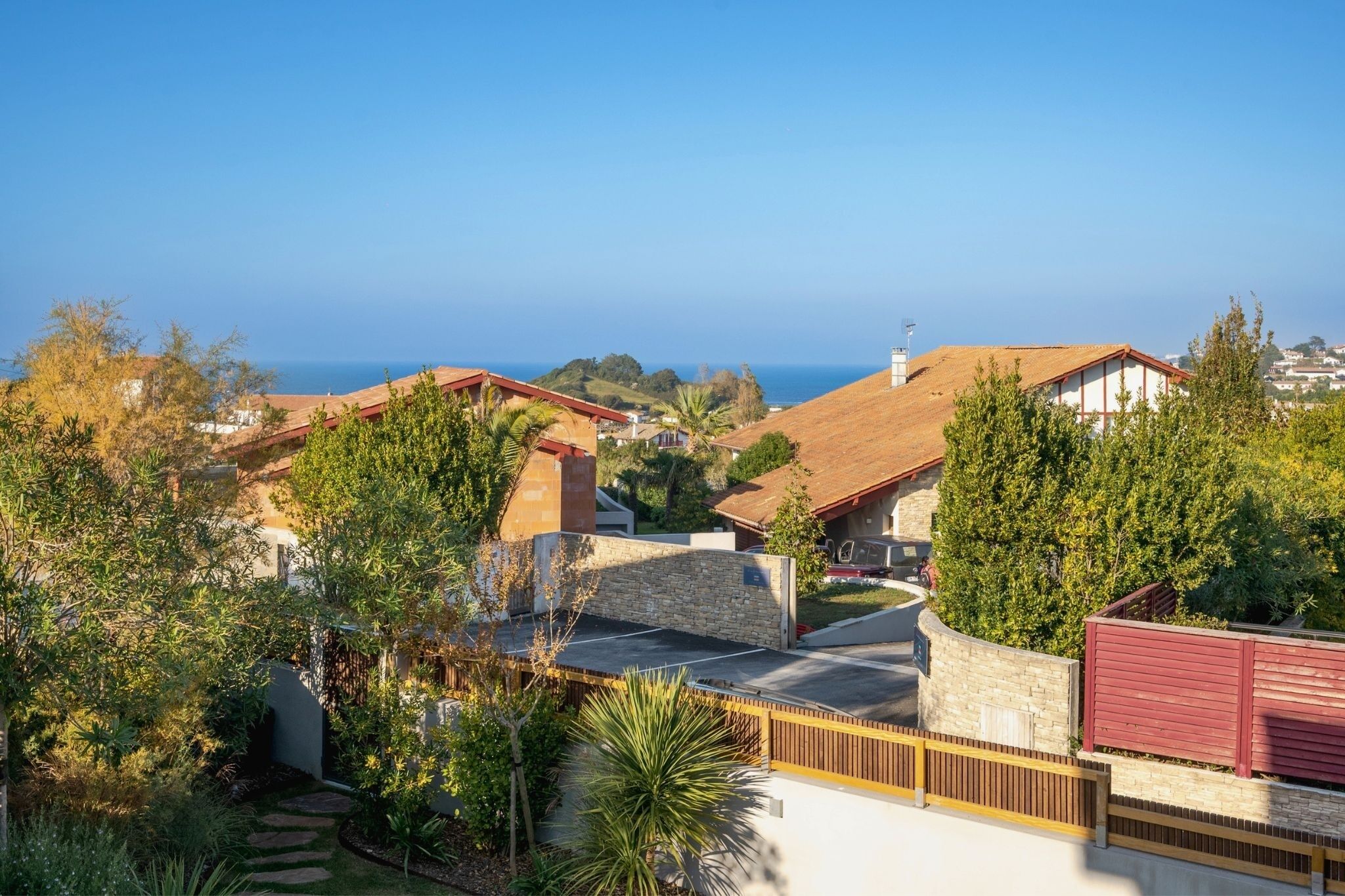 A residential area with houses, a stone wall, and a view of the ocean.