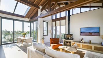 A spacious living area with a high ceiling, large windows, and a comfortable seating arrangement.