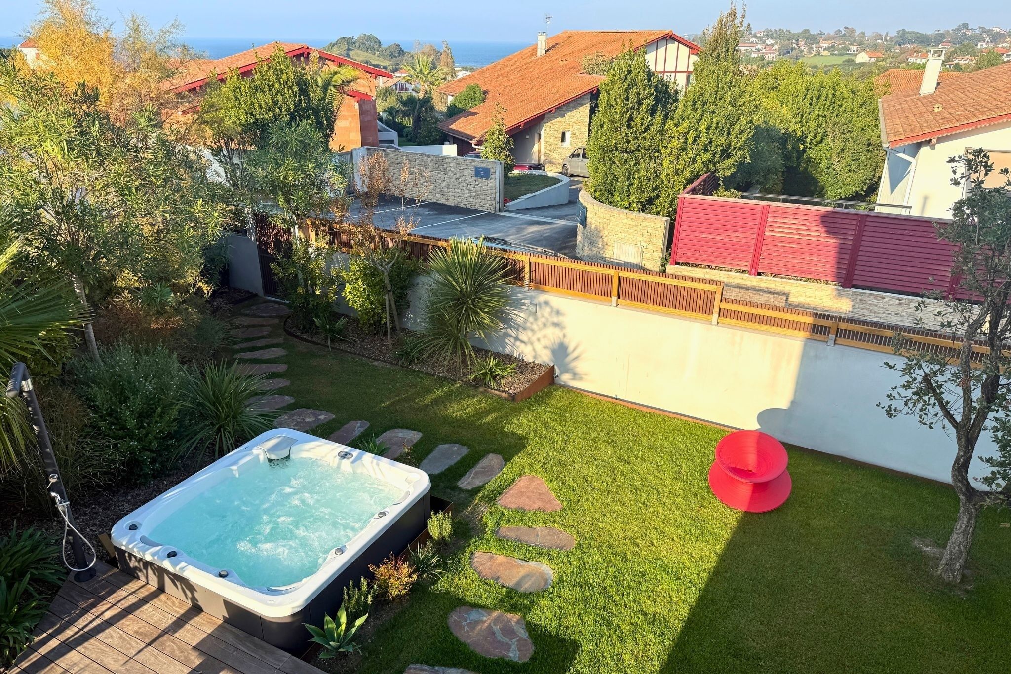 Patio con jacuzzi, escalones de piedra y una silla roja.
