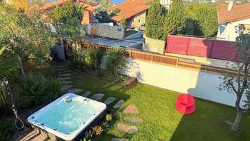 Patio con jacuzzi, escalones de piedra y una silla roja.
