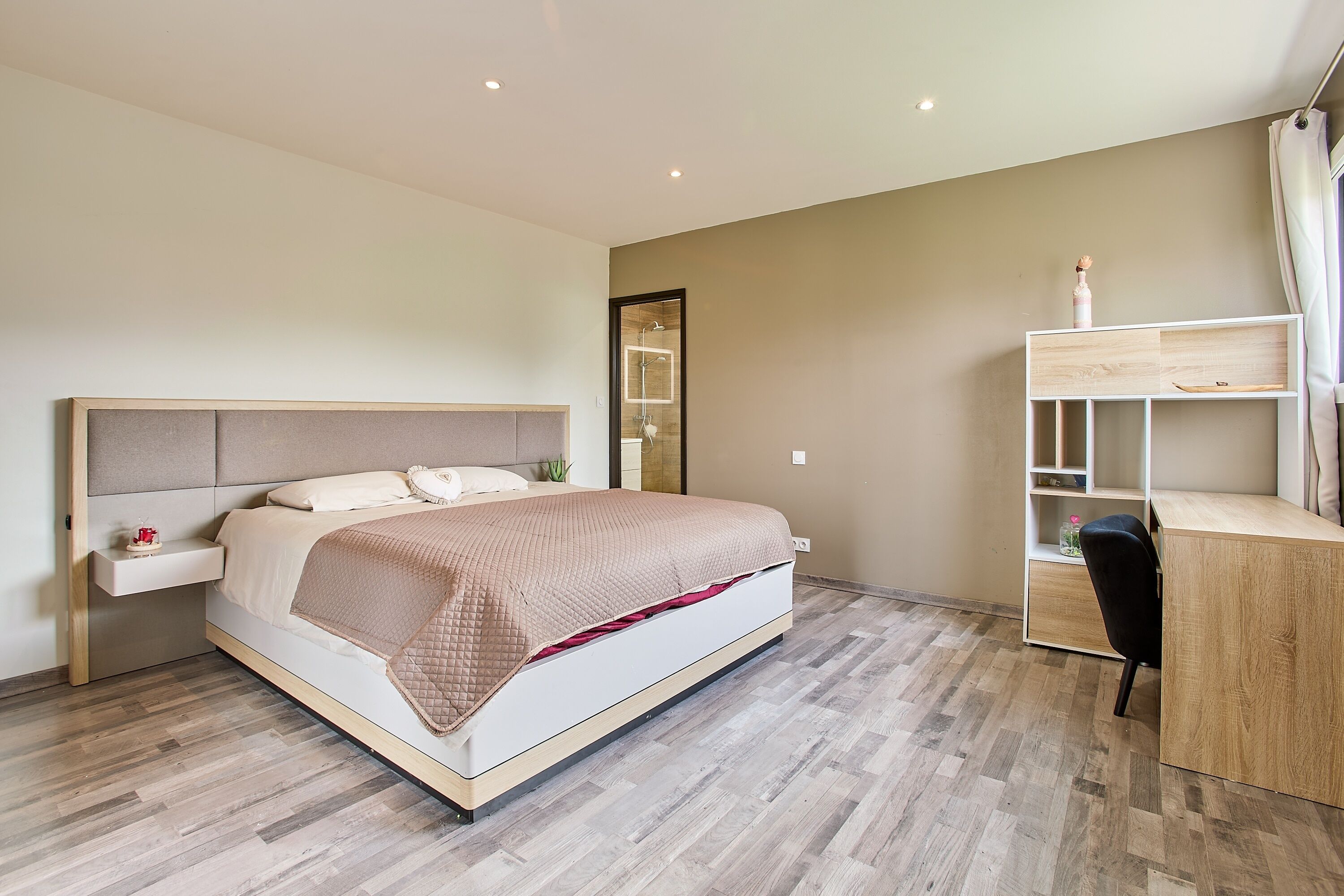 A modern bedroom with a bed, bedside table, and a desk with a chair.