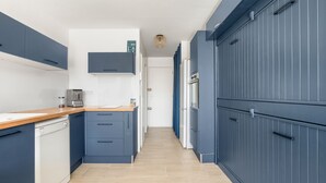 Eine moderne Küche mit blauen Schränken, einem Geschirrspüler und einer Arbeitsplatte mit einer Kaffeemaschine.