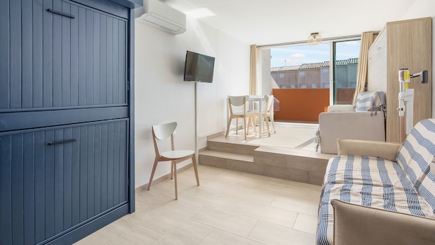 Ein modernes Zimmer mit einem blauen Schrank, einem Flachbildfernseher, einer Couch und Blick ins Freie.