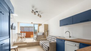 Eine kompakte Küche mit Geschirrspüler, ein Essbereich mit Tisch und Stühlen sowie eine Sitzecke mit Sofa.