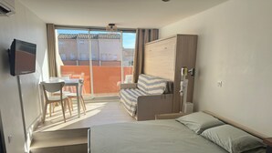 Ein Hotelzimmer mit Bett, Schreibtisch, Stuhl, Kleiderschrank und Fernseher.