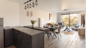 Eine moderne Küche mit einer Kochinsel, Essbereich mit Stühlen, einer Couch und einem großen Fenster mit Aussicht.