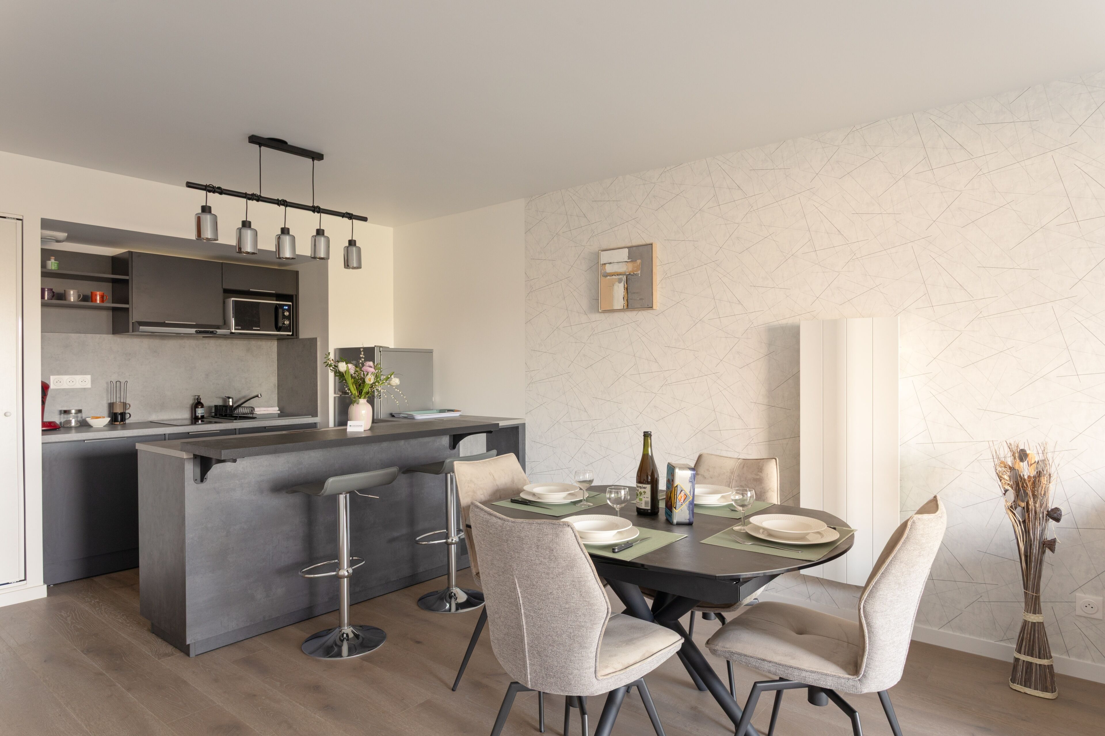 Cozinha moderna com ilha central, banquetas de bar e mesa de jantar posta para quatro pessoas.