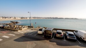 Zona de estacionamiento con vehículos y vistas a la playa y al océano.