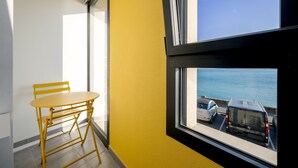 Un balcón con pared amarilla, una mesa y una silla.