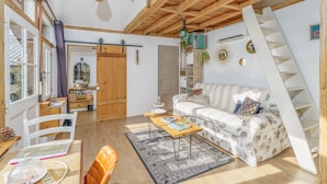 A spacious living area with a wooden staircase, a sofa, a coffee table, and a dining area with chairs. - Les Cabanes de Mamette - sur les hauteurs de Beaune (Beaune)