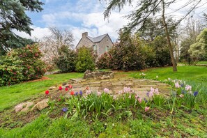 Un bâtiment en pierre doté d’un jardin où l’on peut admirer une grande variété de fleurs, ainsi qu’un sentier en pierre.