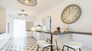 Een moderne keuken met een grote klok, witte kastjes, een bar en een vloer met een patroon.