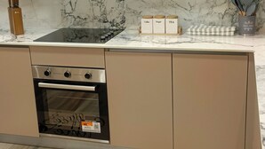 Eine moderne Küche mit einem eingebauten Backofen, einer Edelstahl-Dunstabzugshaube und einer Marmor-Spritzschutzwand.
