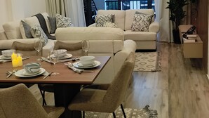 Ein modernes Wohnzimmer mit Essbereich, großen Fenstern und einer Treppe, die zu einer oberen Etage führt.