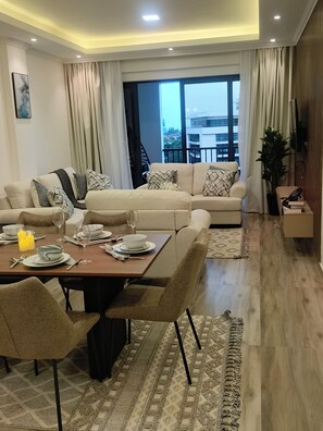 Una sala de estar moderna con comedor, ventanas grandes y una escalera que sube a un nivel superior.
