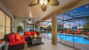 Un espacio al aire libre techado con piscina, mobiliario y una chimenea.