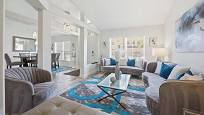 Un salón moderno con una mesa de centro de vidrio, sofás grises y una alfombra azul estampada.
