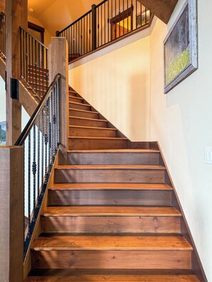 A wooden staircase with a black railing, leading to an upper floor.
