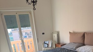 Un dormitorio con cama, televisión y vistas a edificios.