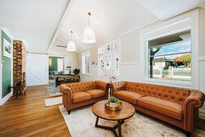 A living room with a sectional sofa, a pool table, and a large window with a view.