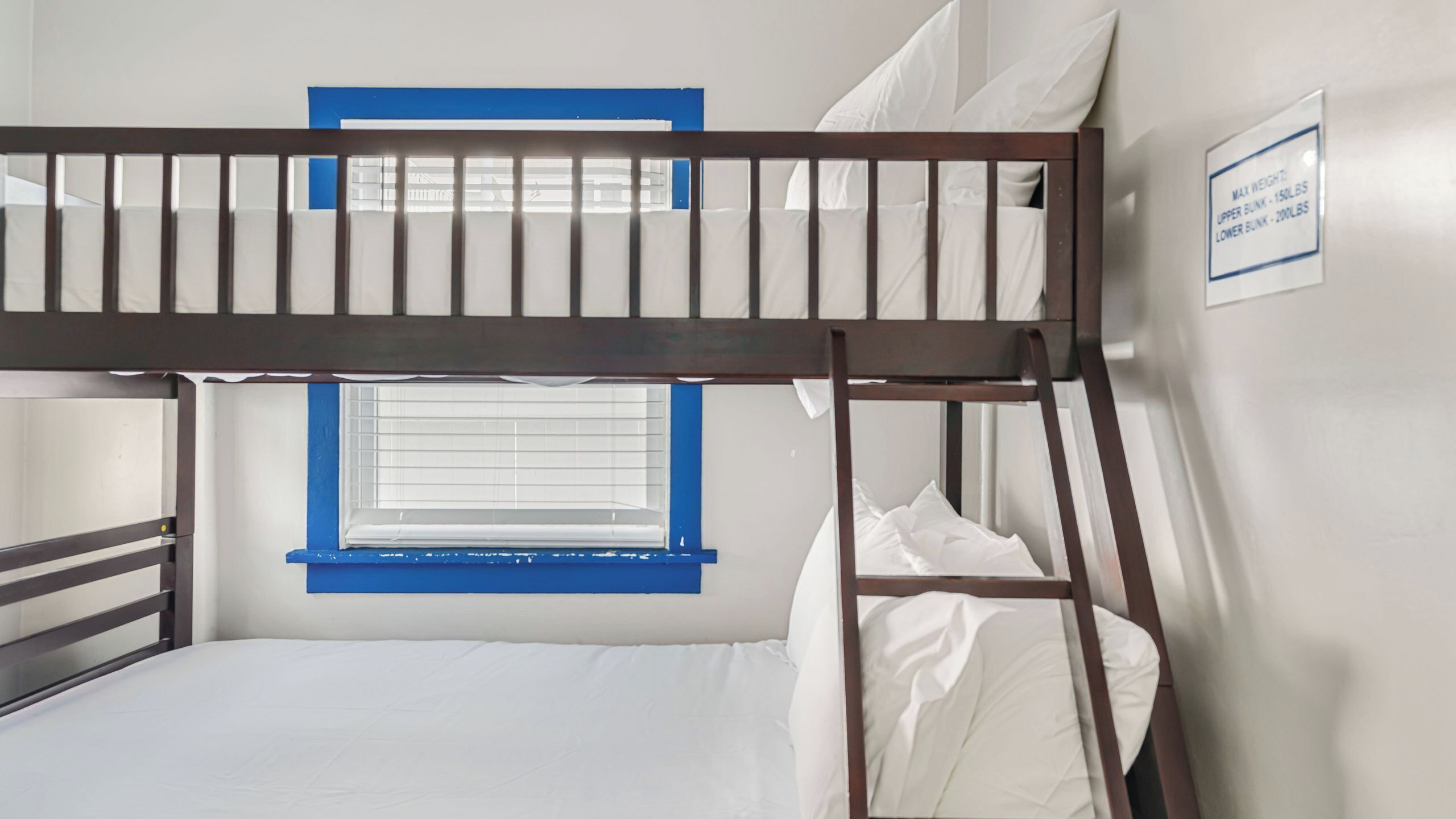 Una cama litera con ventana y un cartel que indica límites de peso.