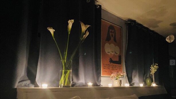A dimly lit room with a bed, a poster on the wall, and a vase with flowers on a table. - Artist’s Studio Steps from Sunset Plaza. Prime West Hollywood Location (West Hollywood)